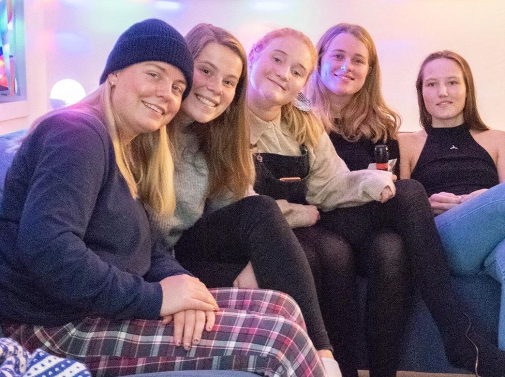 Elever sitter i en sofa kledd i ullundertøy og pysjbukser.