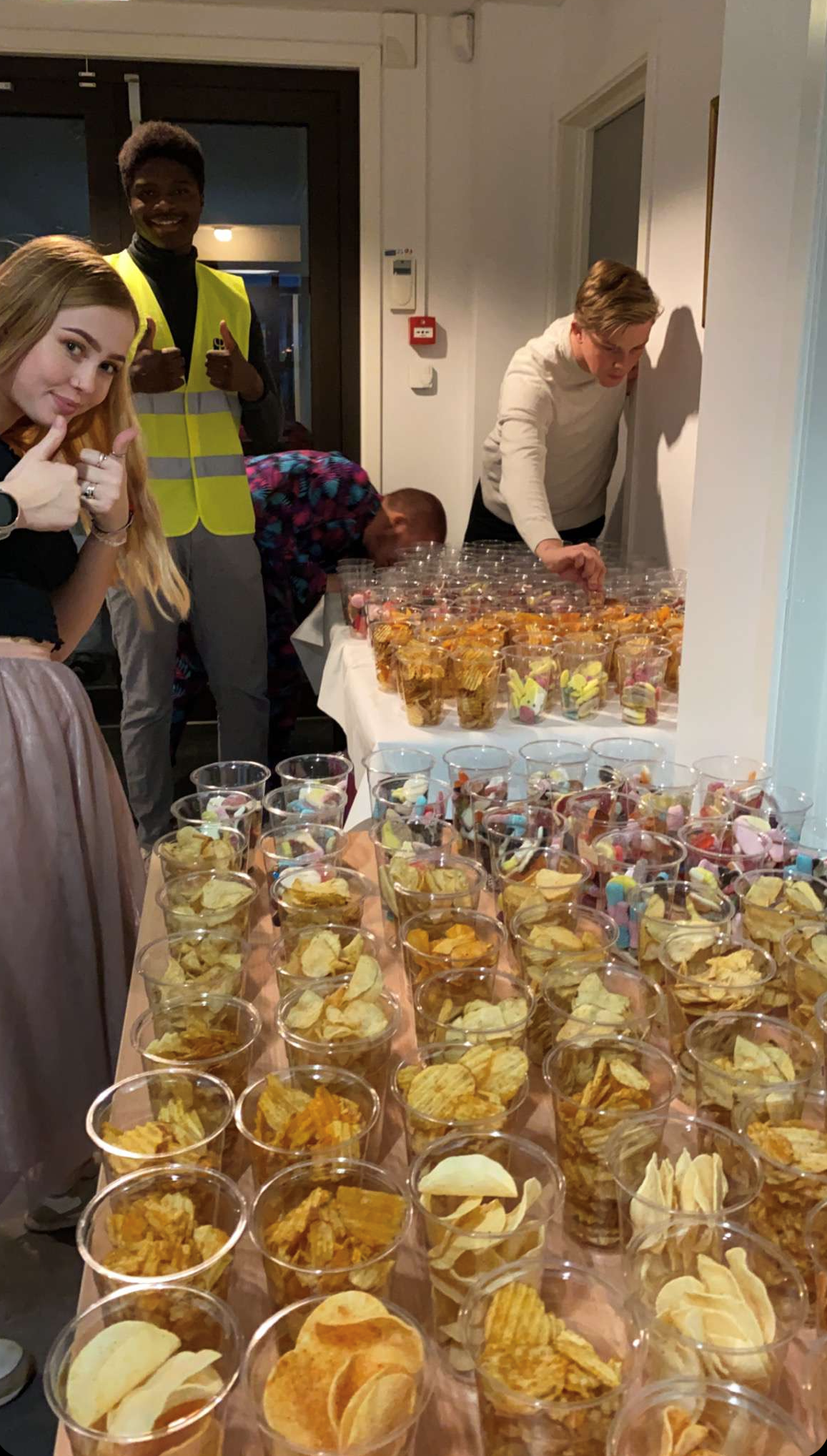 to bord fulle av engangskopper fylt med potetgull og smågodt,