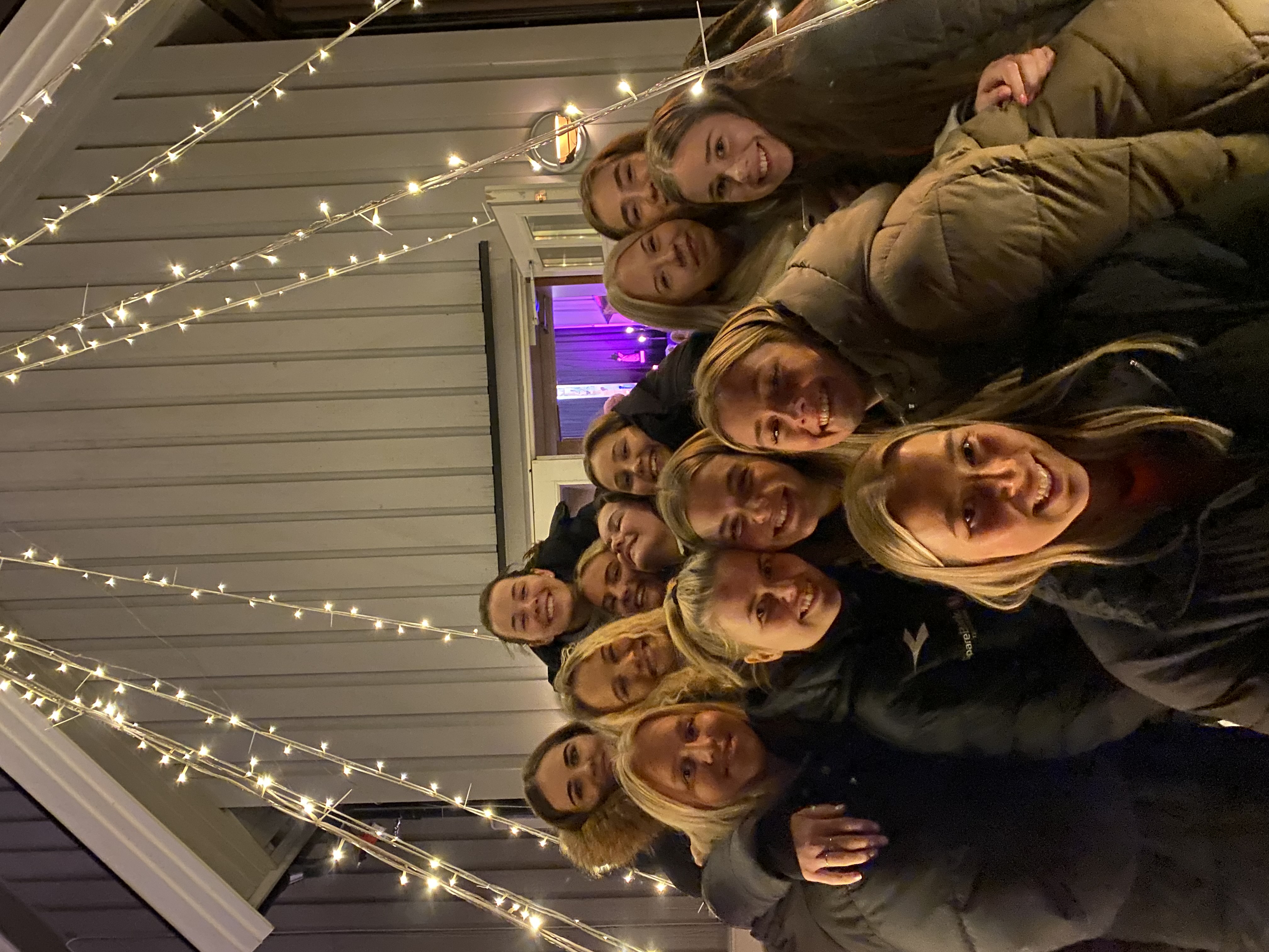 klemmebilde. 12 jenter klemmer under julelys. utendørs i mørket