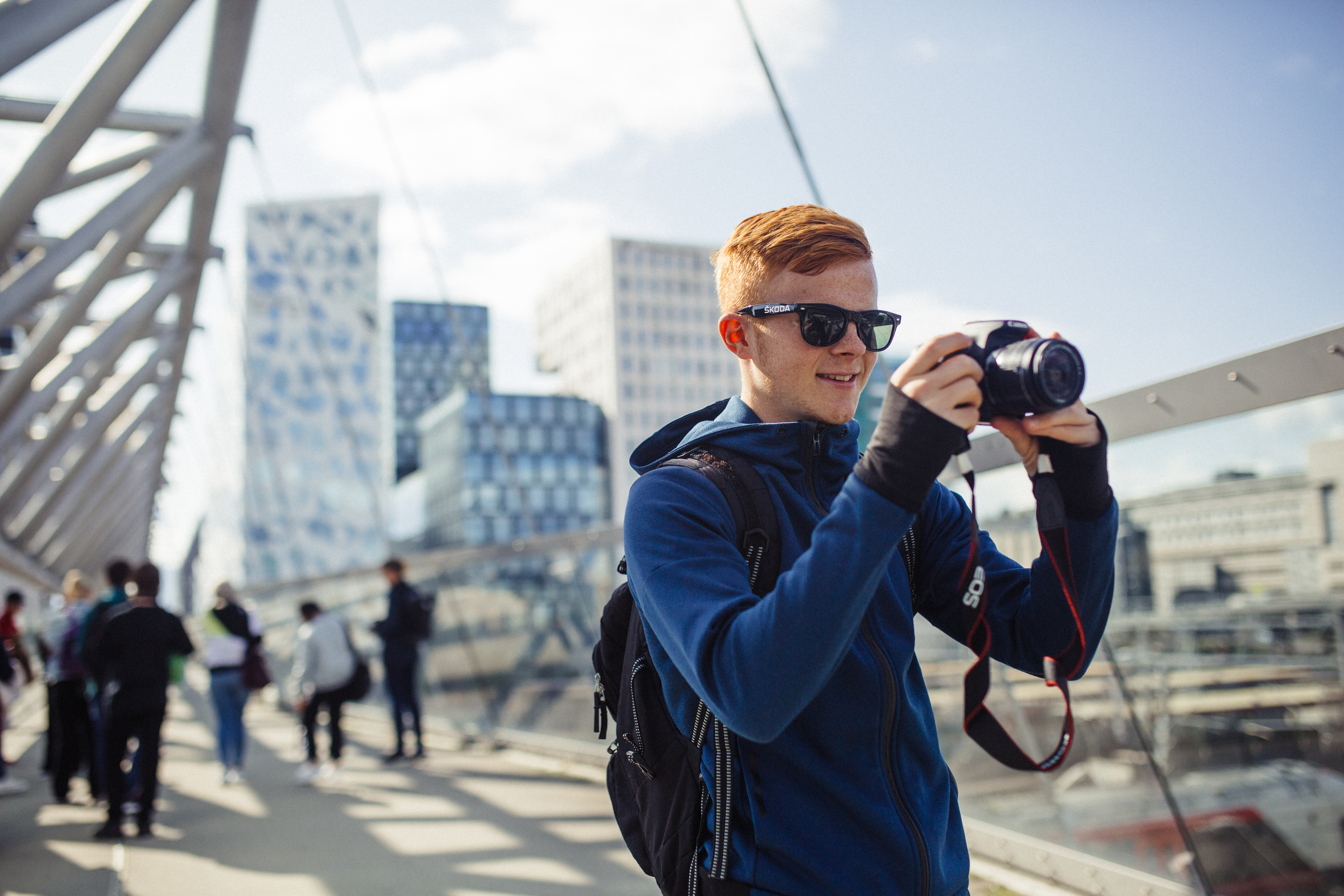 En ung mann tar bilder i sentrum av Oslo. Du ser barcodebygningene i bakgrunnen.