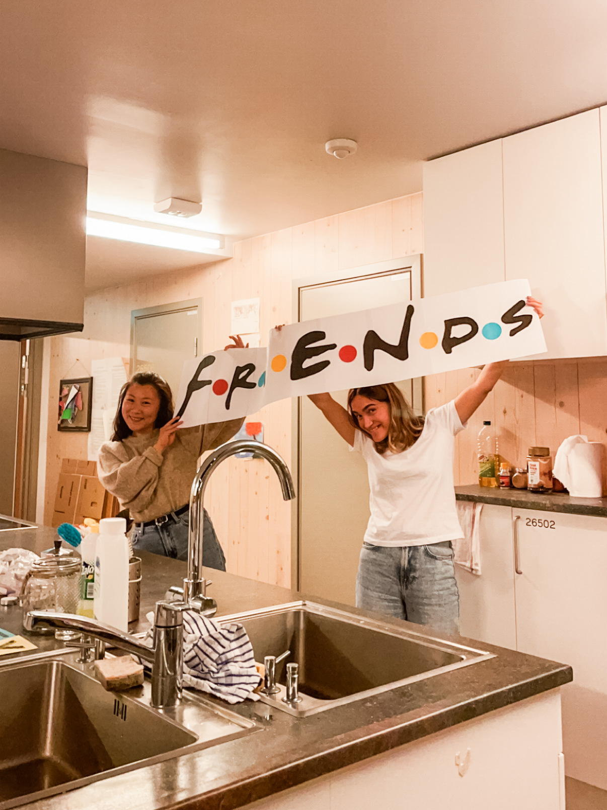 To unge kvinner på et studentkjøkken, De holder opp en plakat med teksten 
