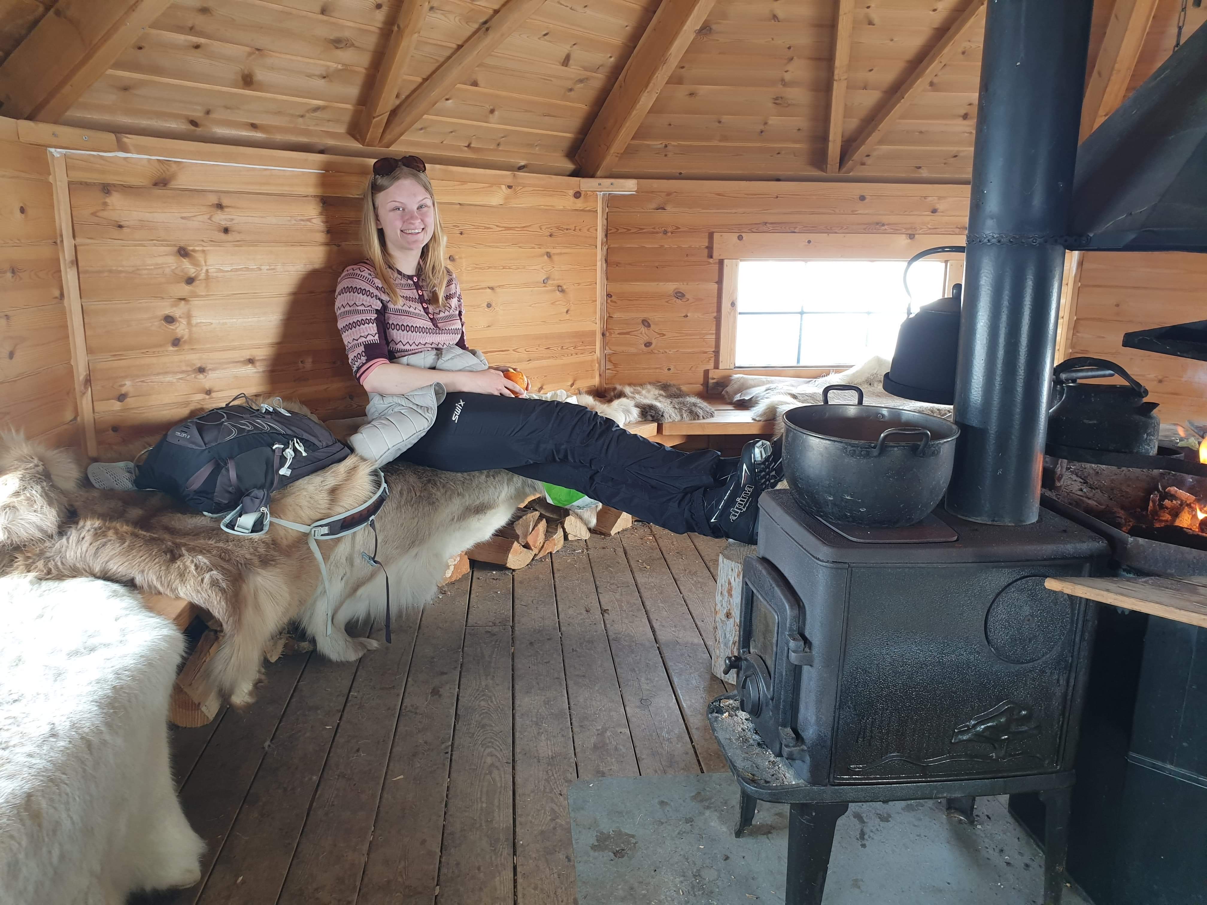 En ung kvinne sitter inne i en enkel hytte.