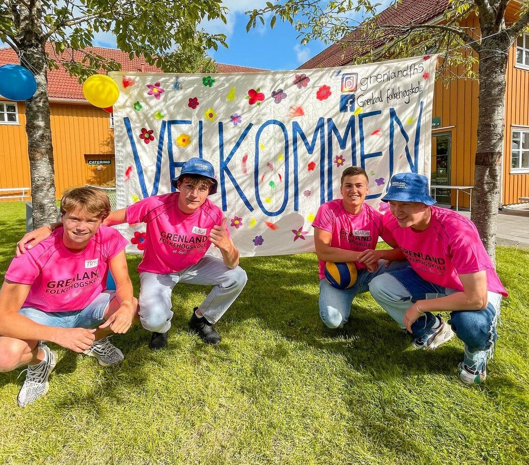 Bilde av fire gutter foran skilt der det står