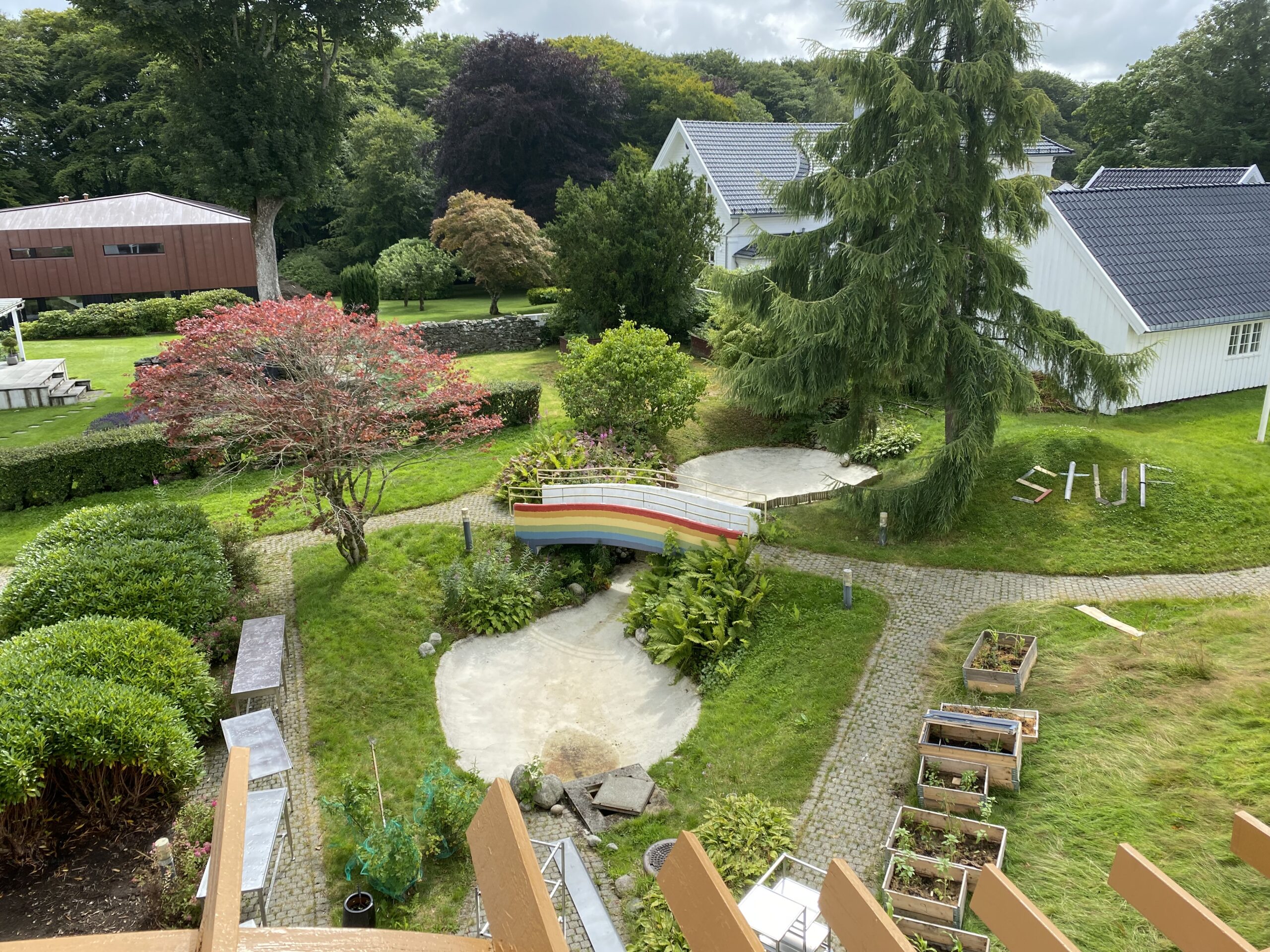 Bilde av hage med plantekasser og regnbuebro. 