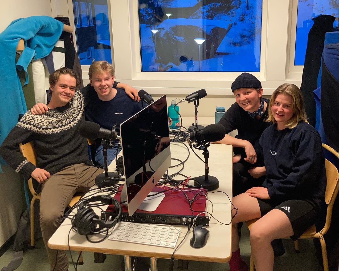 Fire personer som sitter rundt podcastutstyr