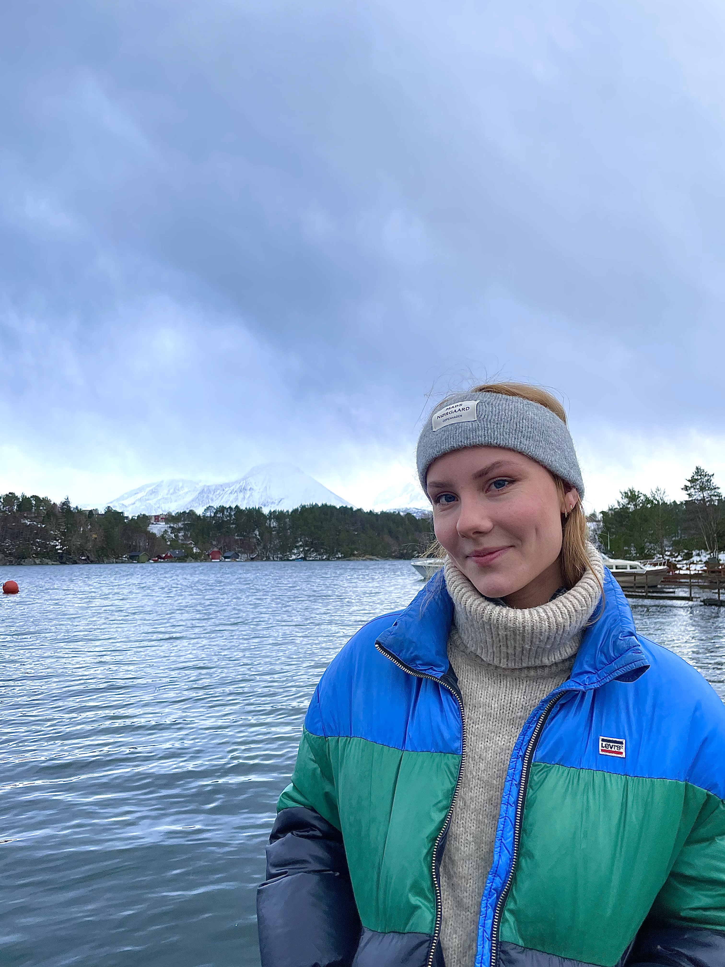 Elev står foran et vann i vinterjakke og ser i kamera.