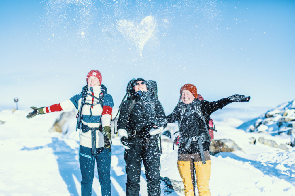 Elever på tur om vinteren. De kastar snø i været og et hjerte synes på himmelen.