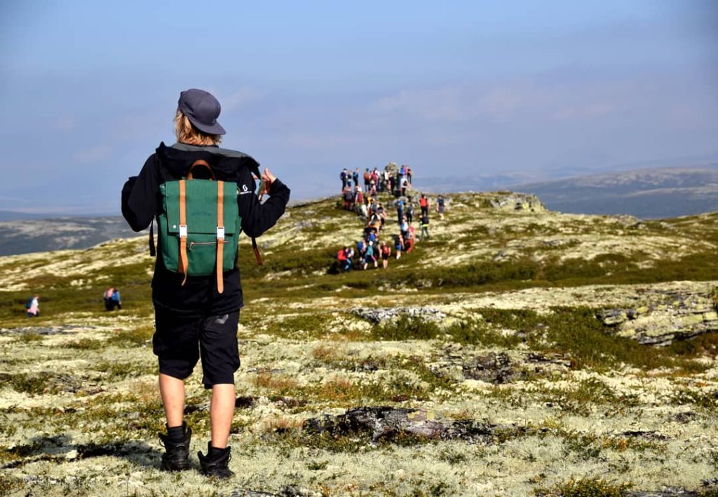 Elev med ryggen til og rygsekk går på fjelltur.
