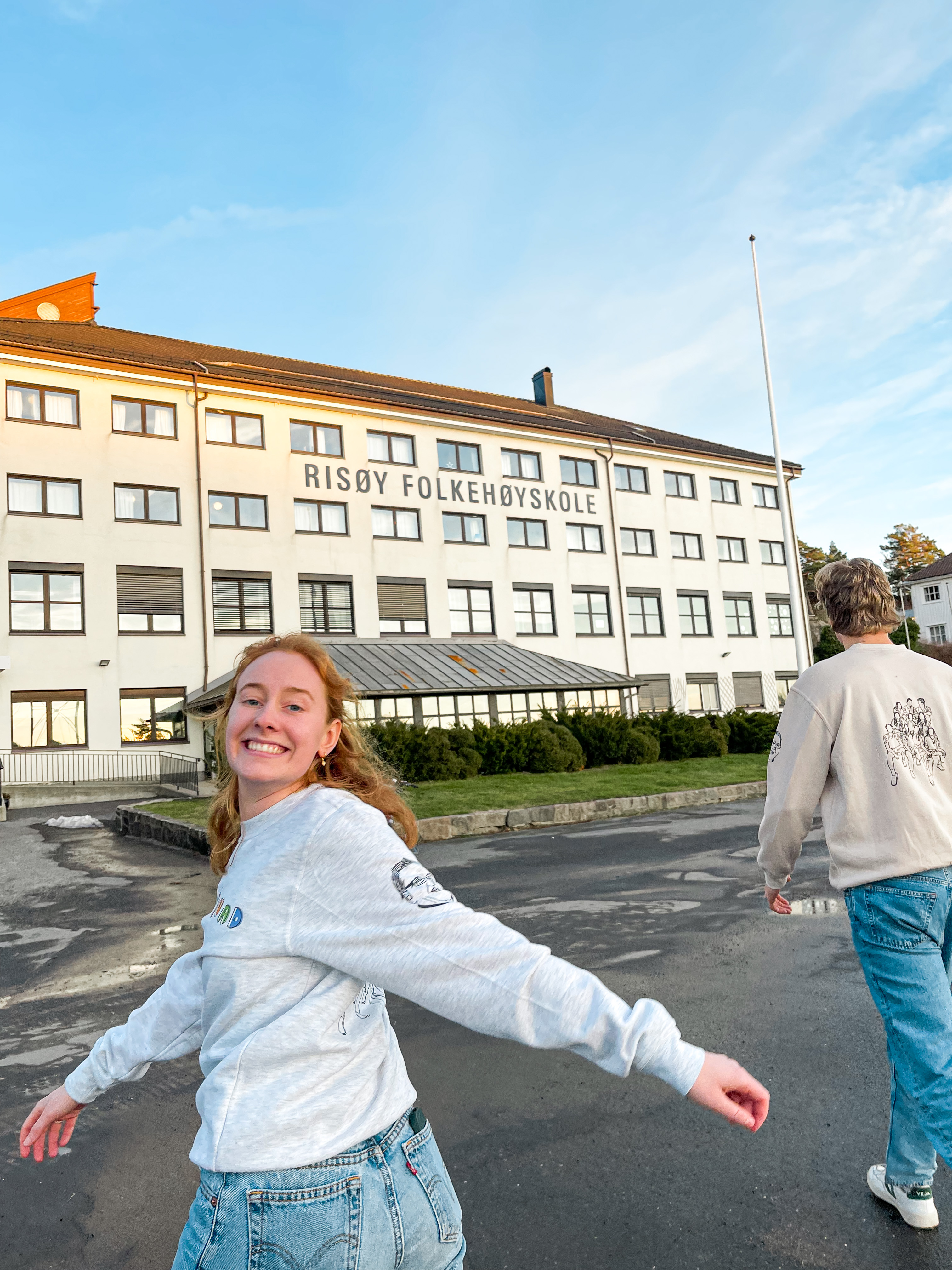 To elever går mot en skolebygning. En ung kvinne snur seg mot kameraet, mens en ung mann har ryggen til.