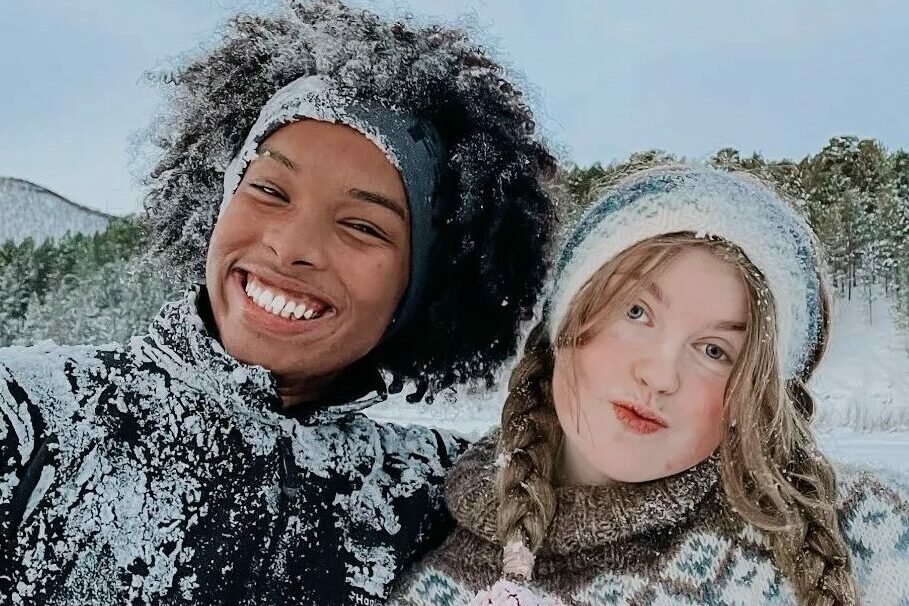 To personer står tett sammen med snø på klær og i håret