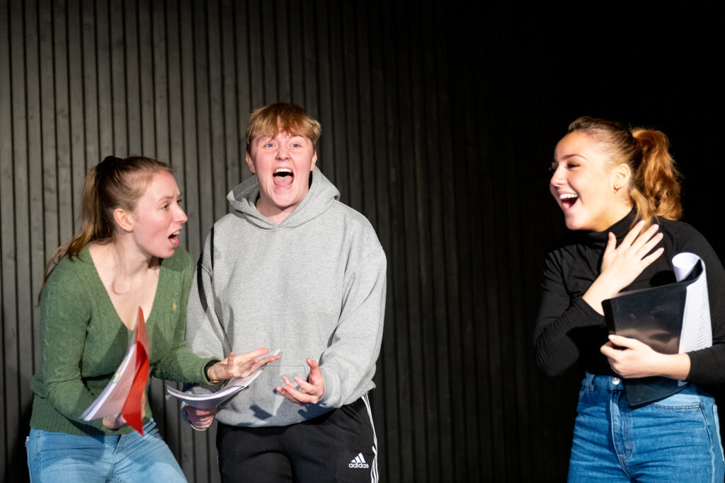 Elever øver på et teaterstykke på en scene.