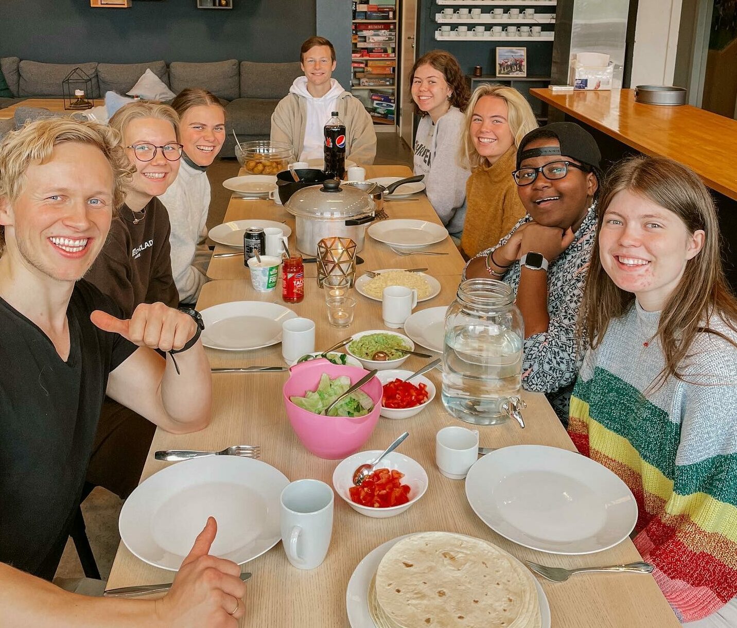 Elever på Helgeland folkehøgskole rundt et bor med tallerkener og mat