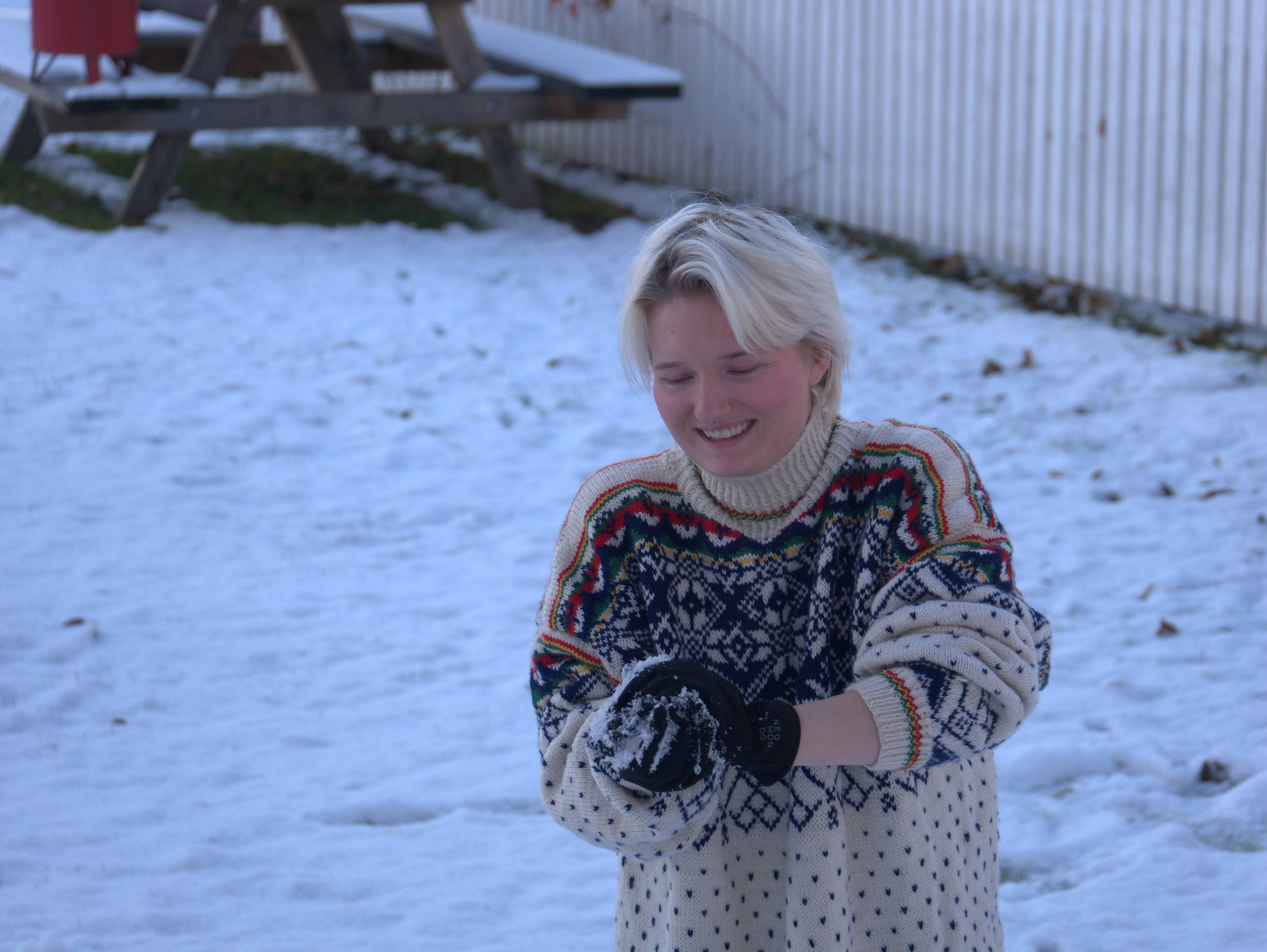 Elev kaster snøball ute om vinteren i strikkegenser.