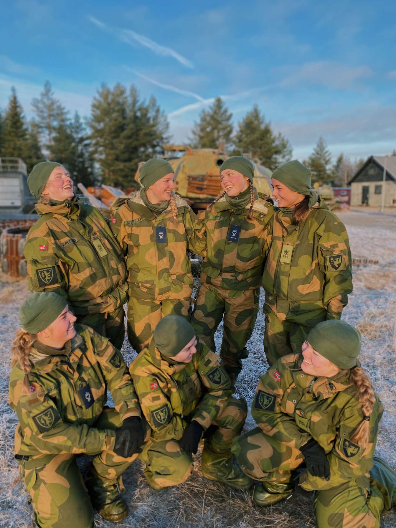 En gjeng med kvinnelige soldater i uniform smiler mot hverandre.