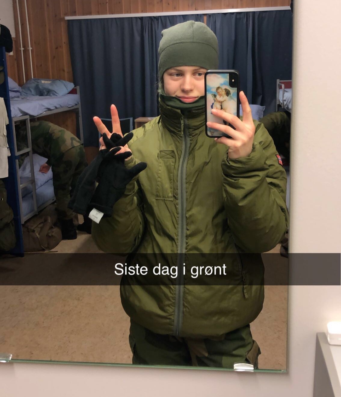 Speilselfie av en kvinnelig soldat som viser peacetegn. På bildet står det 