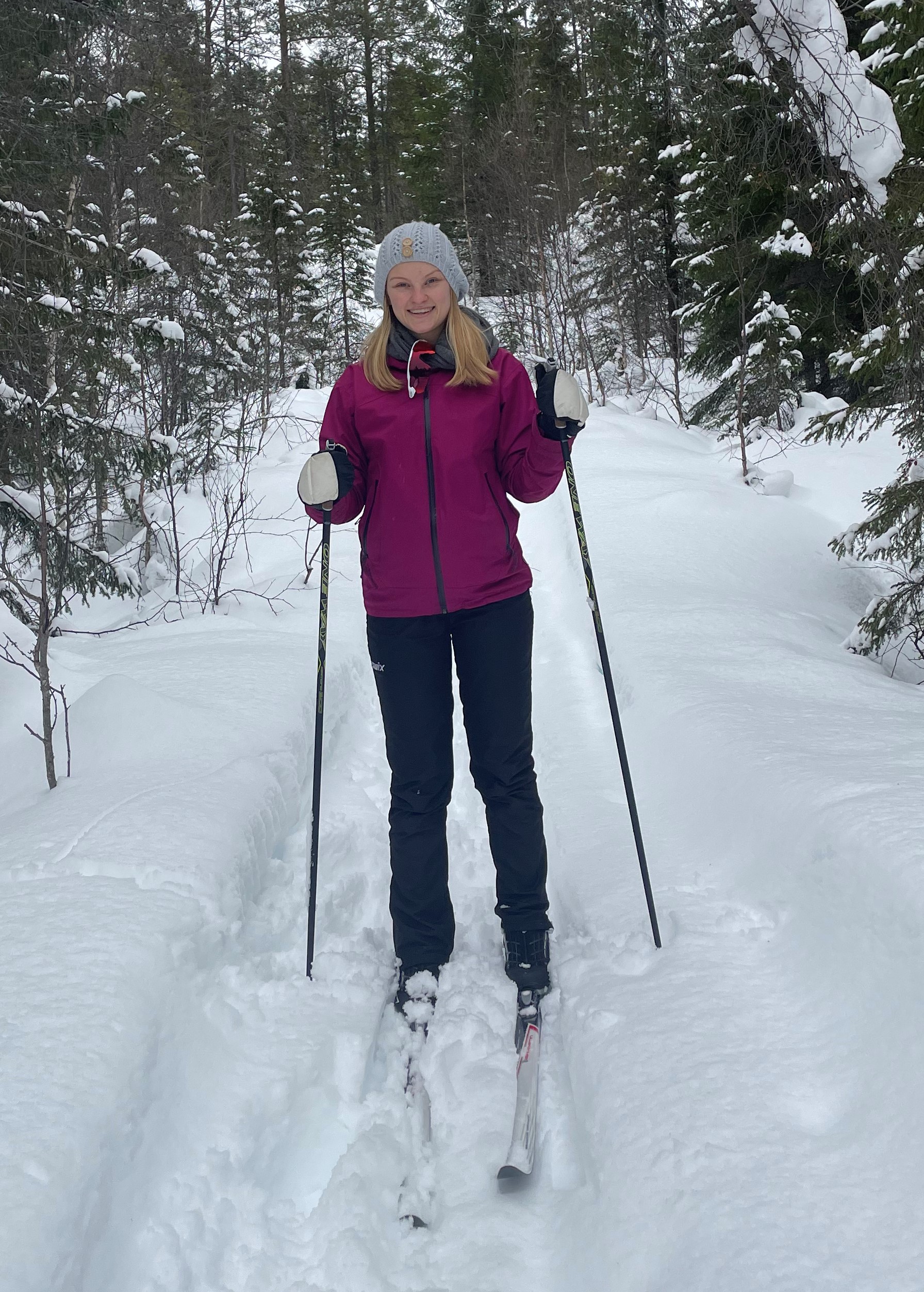 En ung kvinne går på langrennsski i en snøfylt skog.