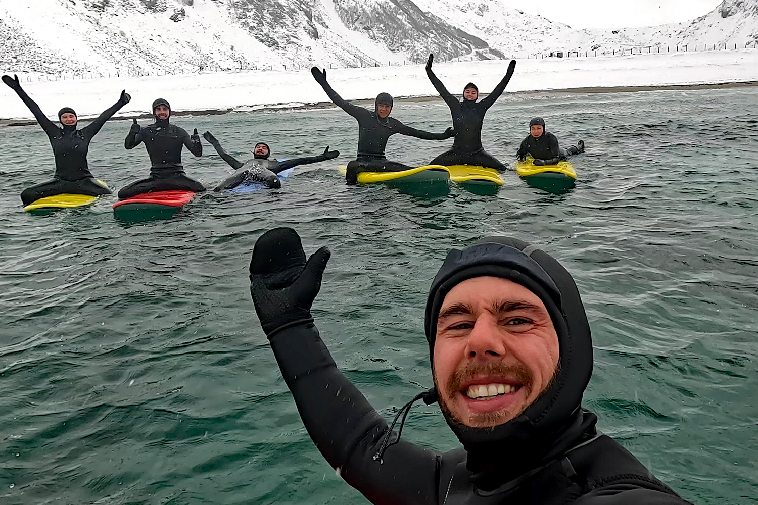 Lærer med elever og fjell i bakgrunnen. arktisk surf i Lofoten.