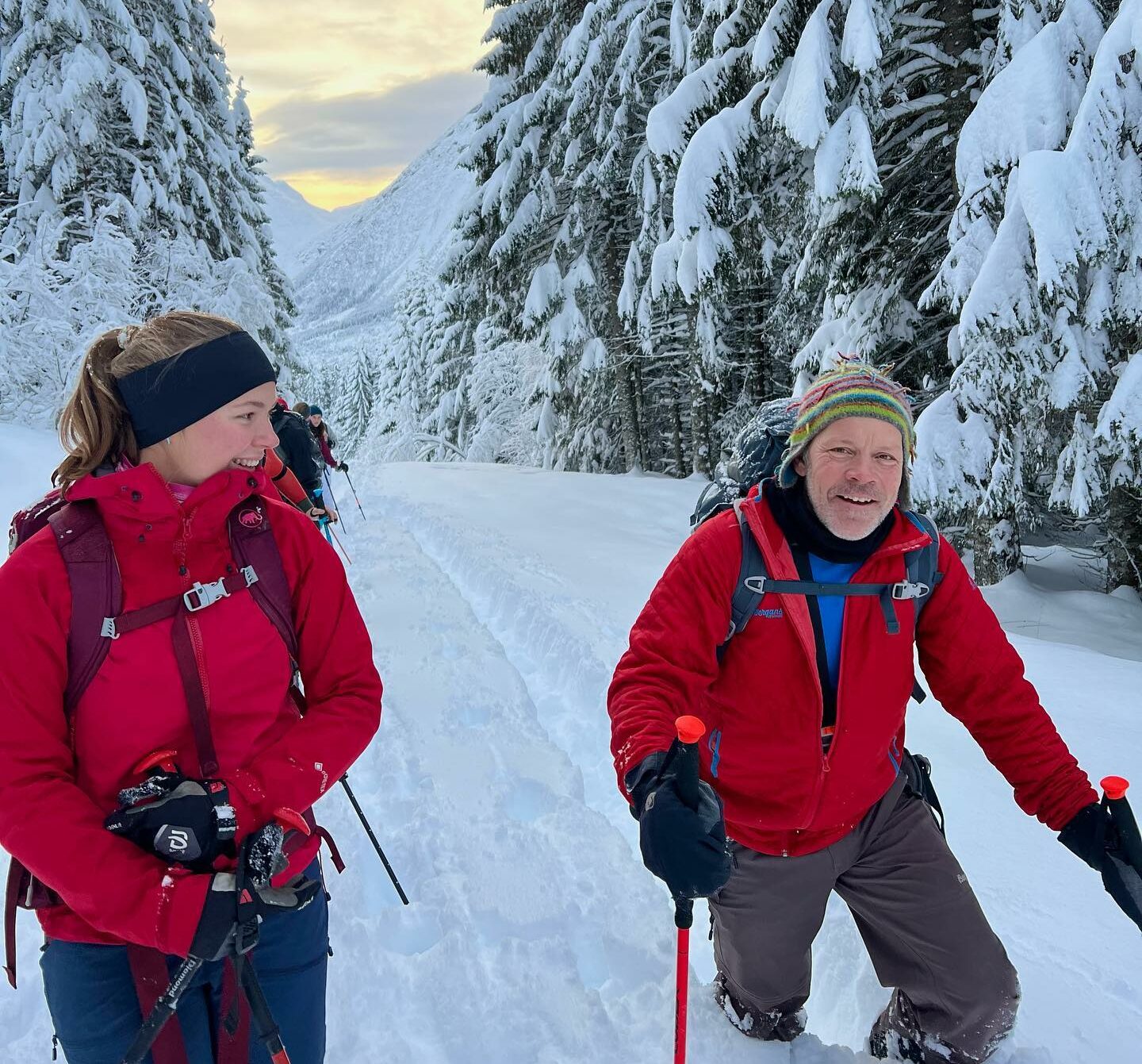 To personer går i dyp snø i en skog. En er en del eldre enn den andre