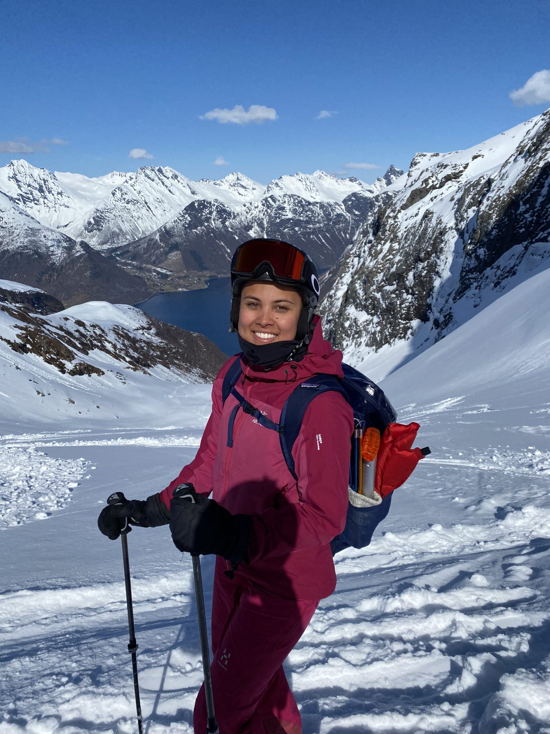 En ung jente på ski smiler i kamera.
