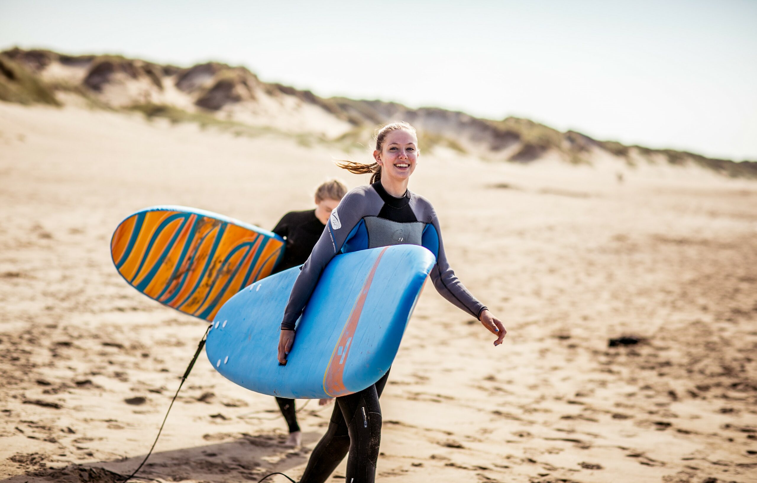 En ung jente holder et surfebrett på en strand. 