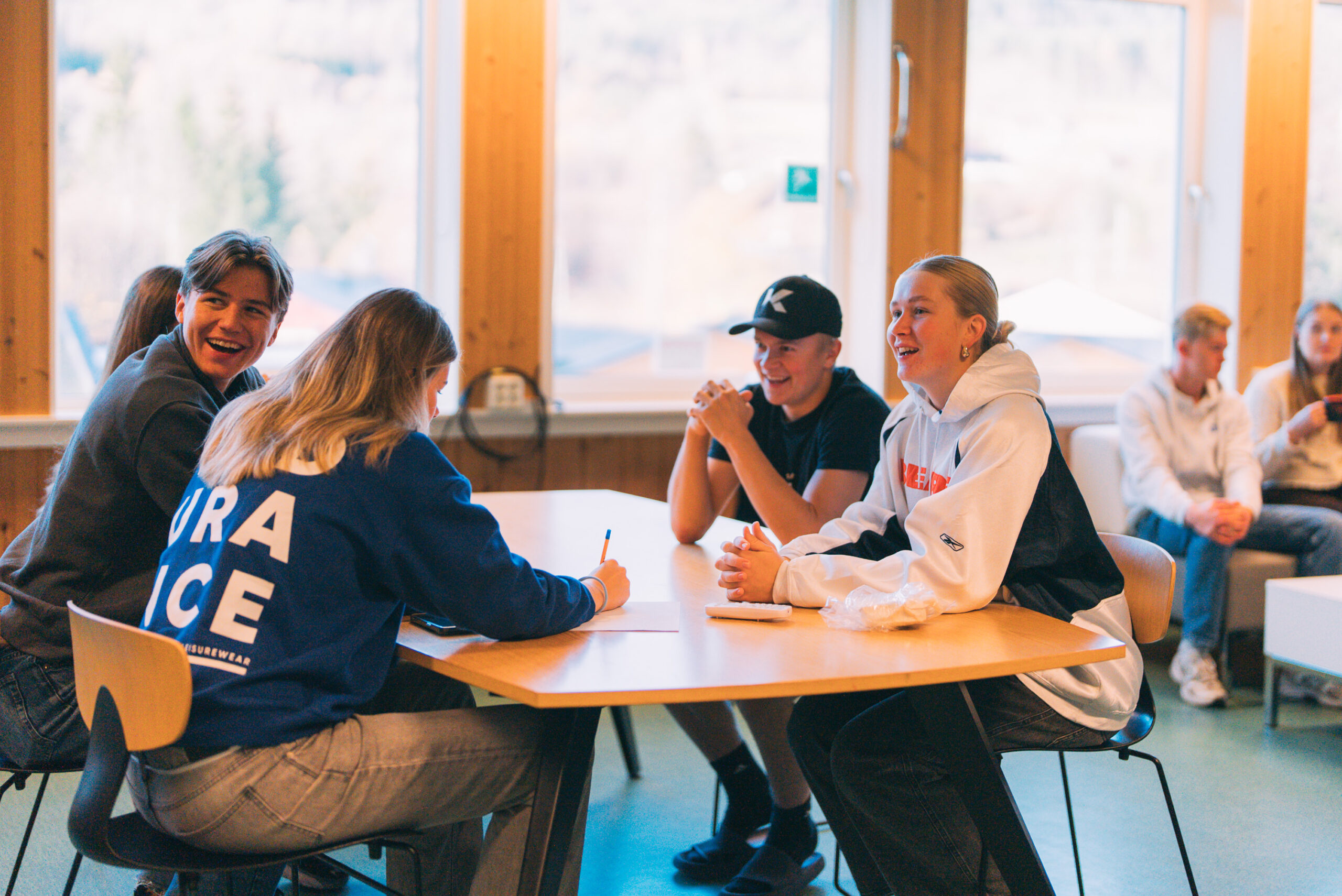 Flere unge sitter på et bord og snakker sammen 