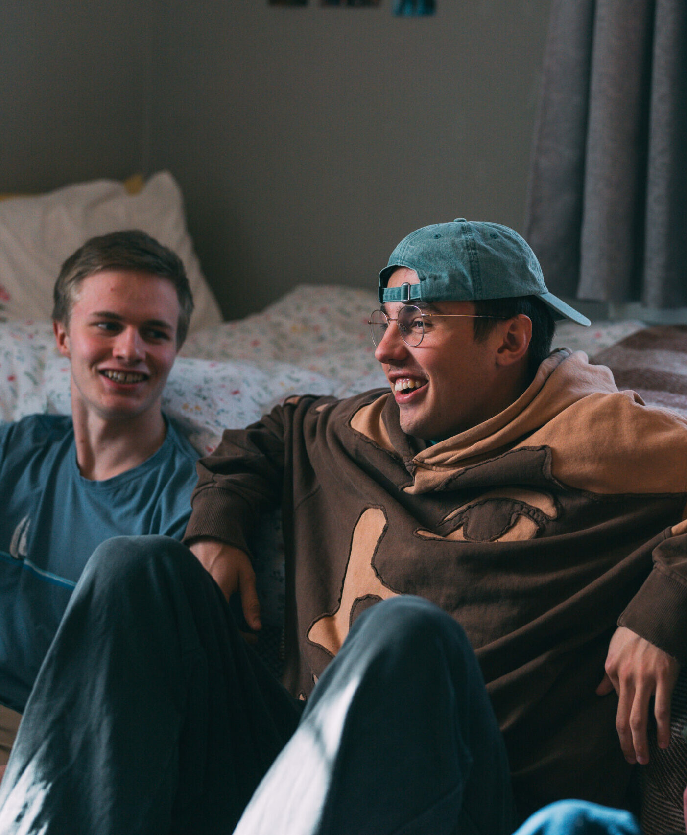 To unge menn lener seg mot senga og ler på internatet