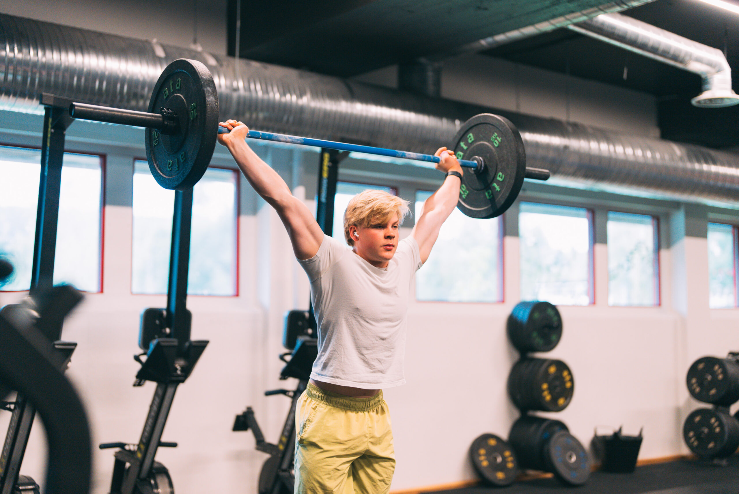 en ung mann løfter opp en stang på et treningssenter 