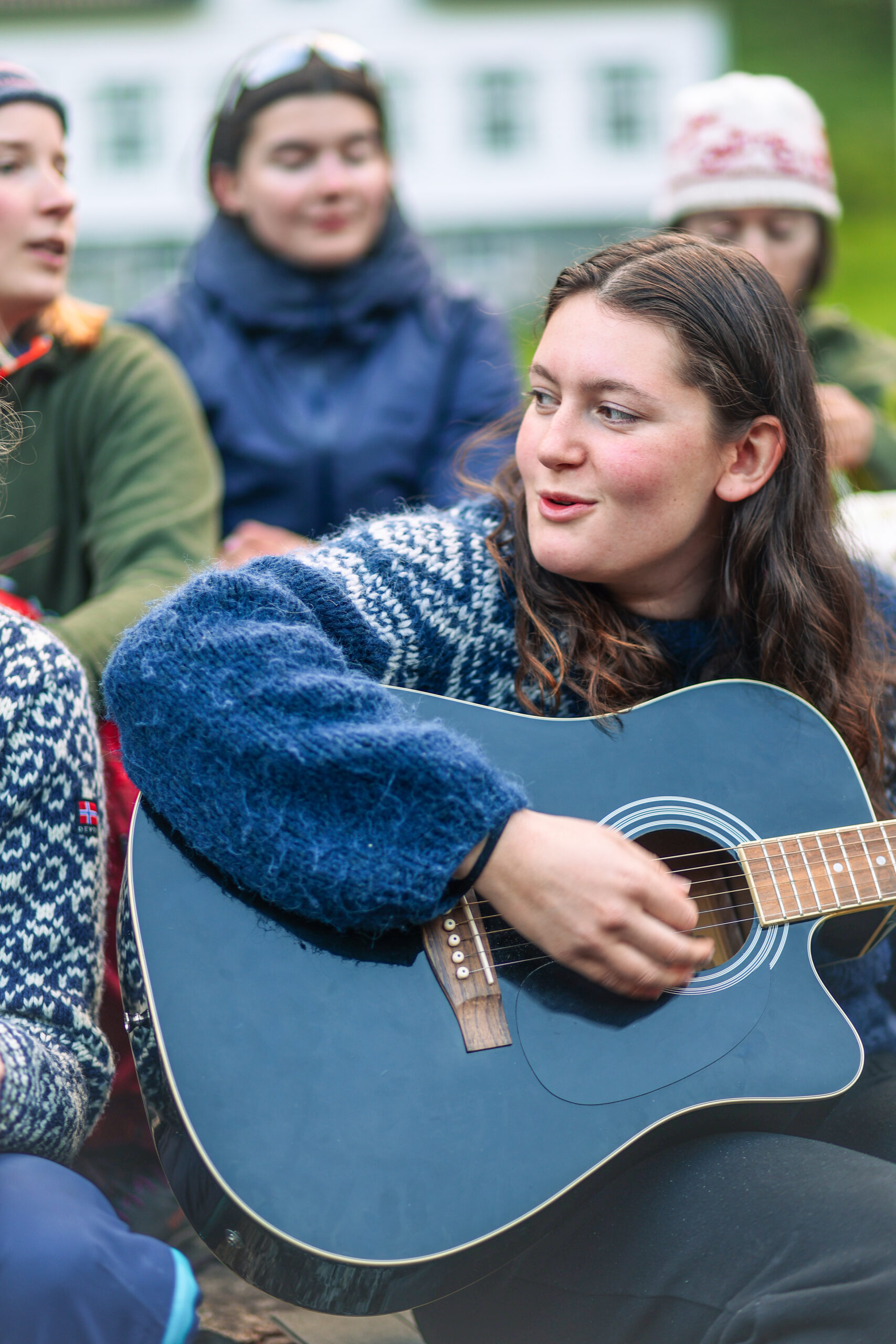 En ung jente i strikkegenser spiller gitar