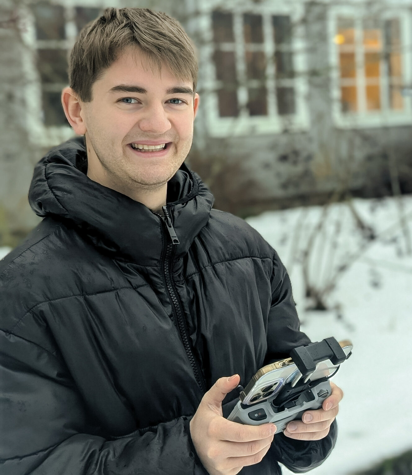 bilde av en ung mann som styrer en drone mens han smiler til kamera