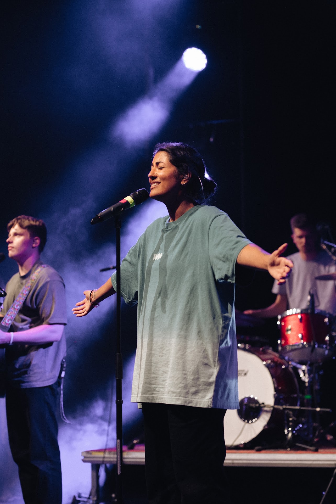 en ung kvinne synger på scenen med lukkede øyne og hendene ute