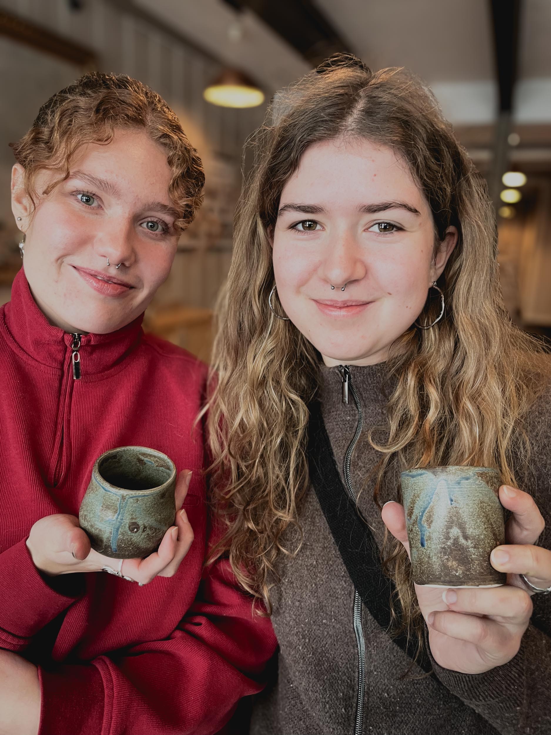 To unge kvinner som holder keramikkopper
