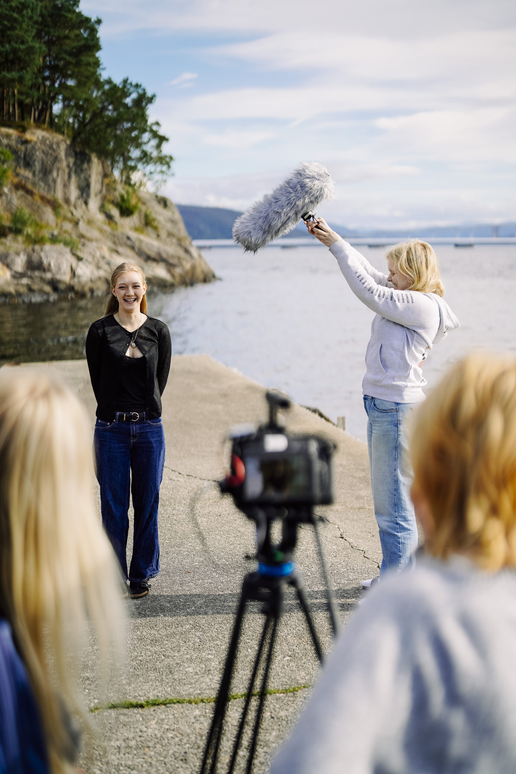 en ung kvinne som blir filmet, en annet ung kvinne holder en mikrofon over henne