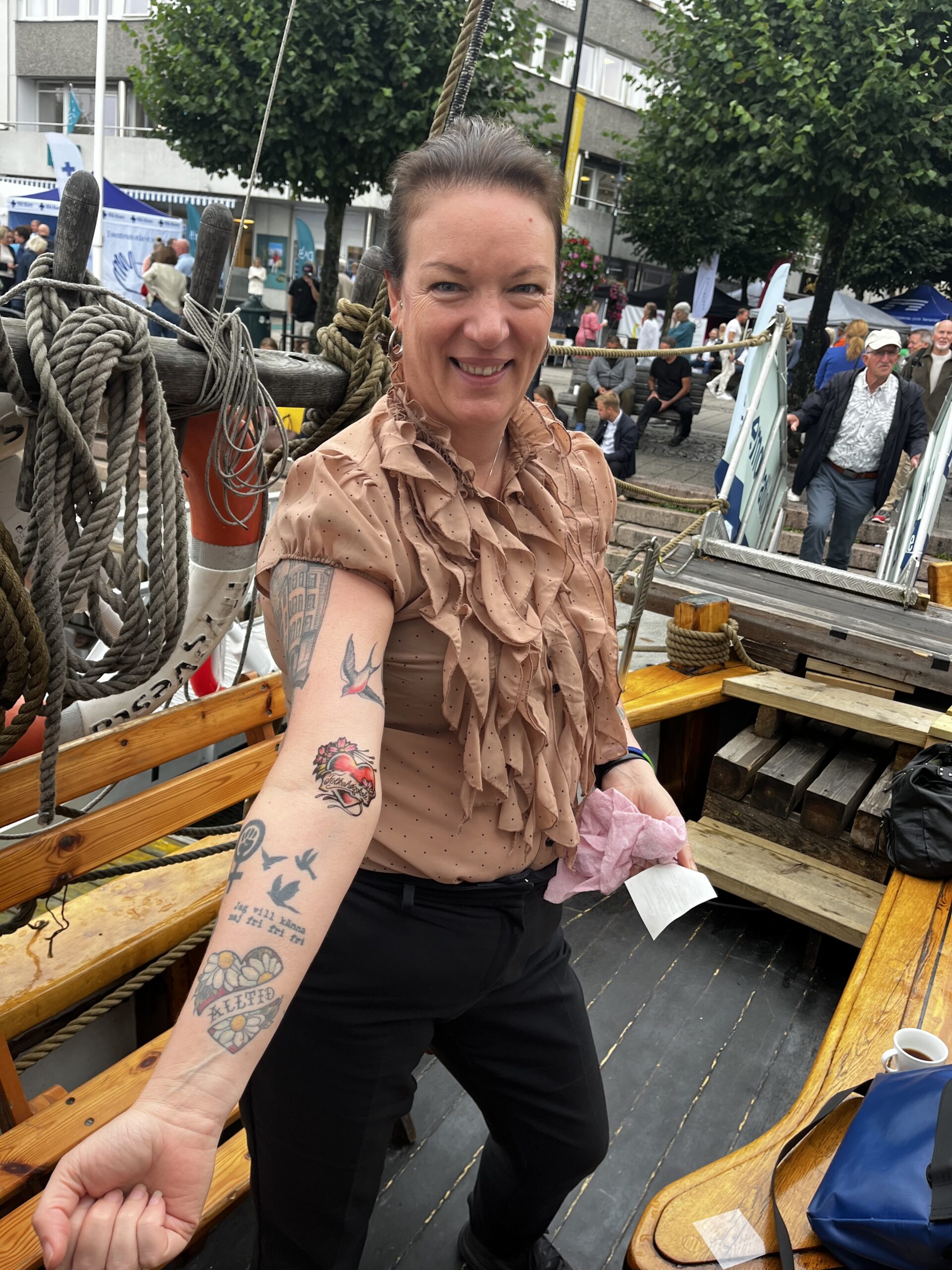 En dame med tatoveringer smiler i kamera