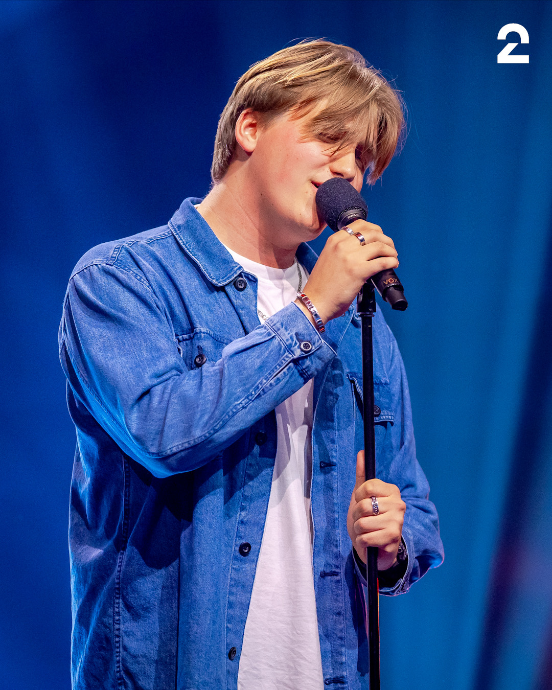Herman i blå skjorte synger i en mikrofon