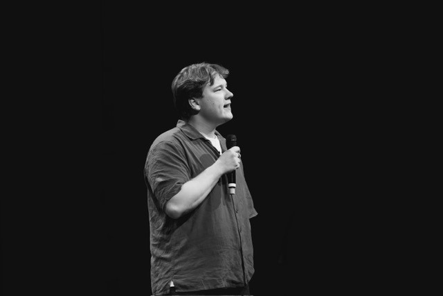 Svart hvitt bilde av Jørgen som står på scenen. 