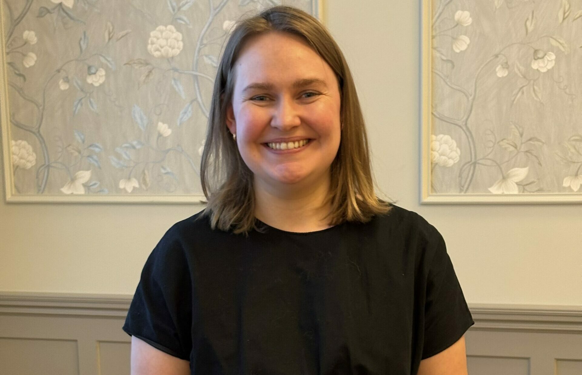 kvinne i en sal som smiler mot kamera