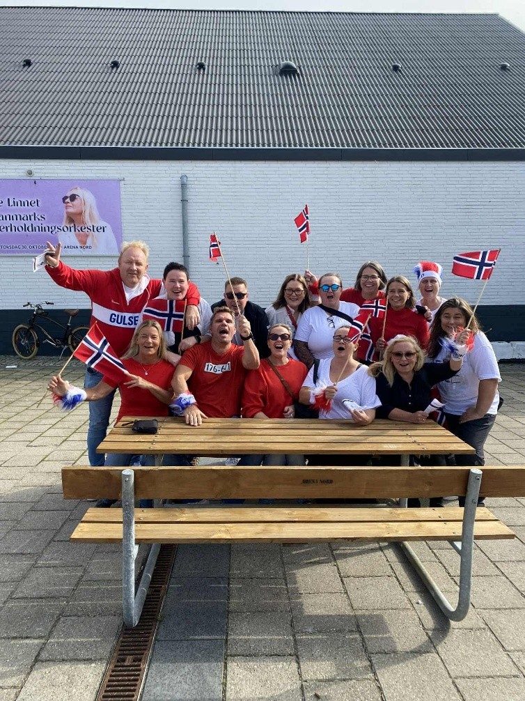 en gruppe mennesker som sitter samlet på et bord med norske flagg