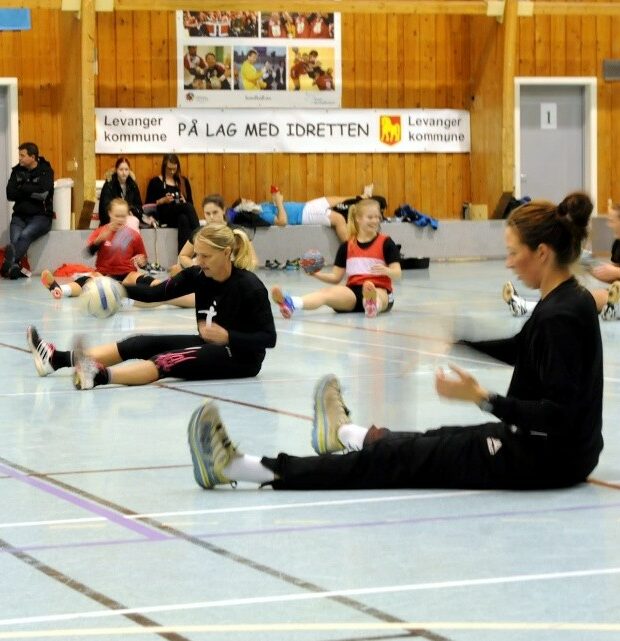 håndballspillere som sitter på gulvet og stusser baller
