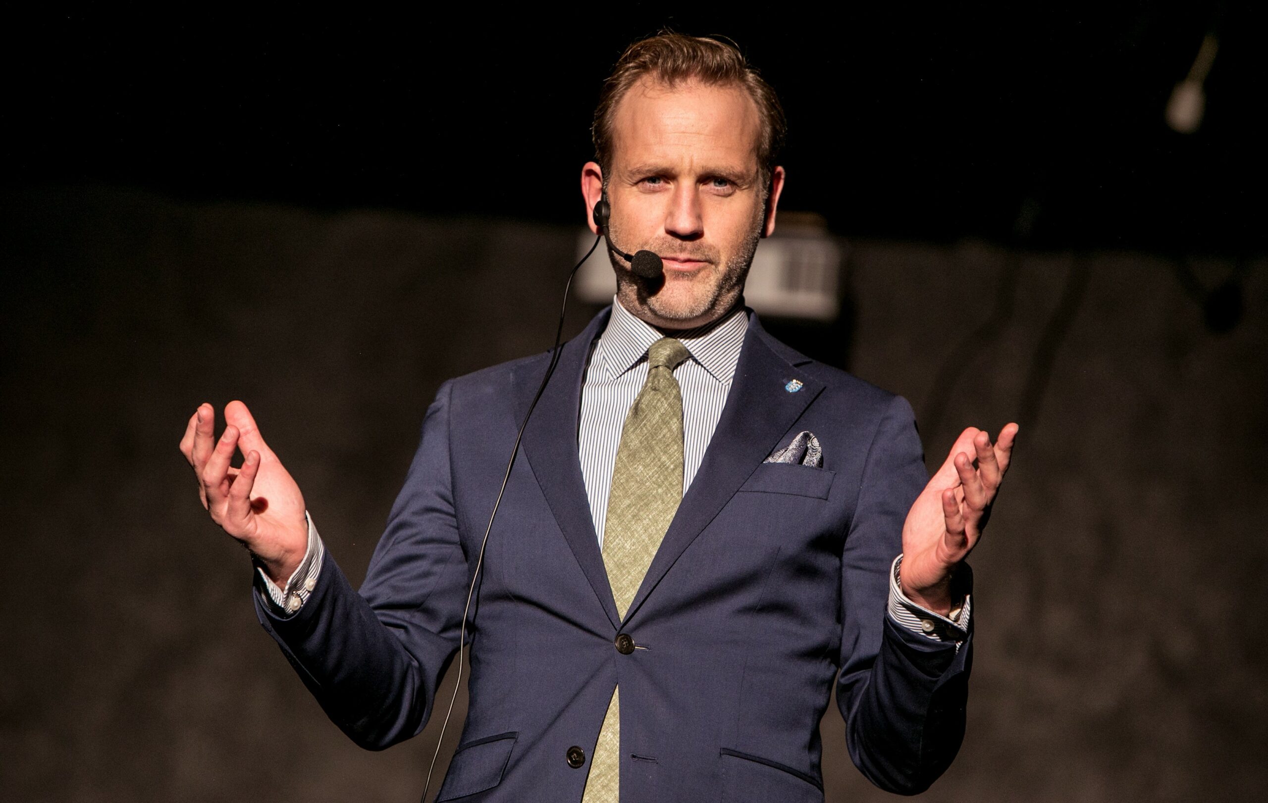 Bilde av en mann med mikrofon på en scene. 