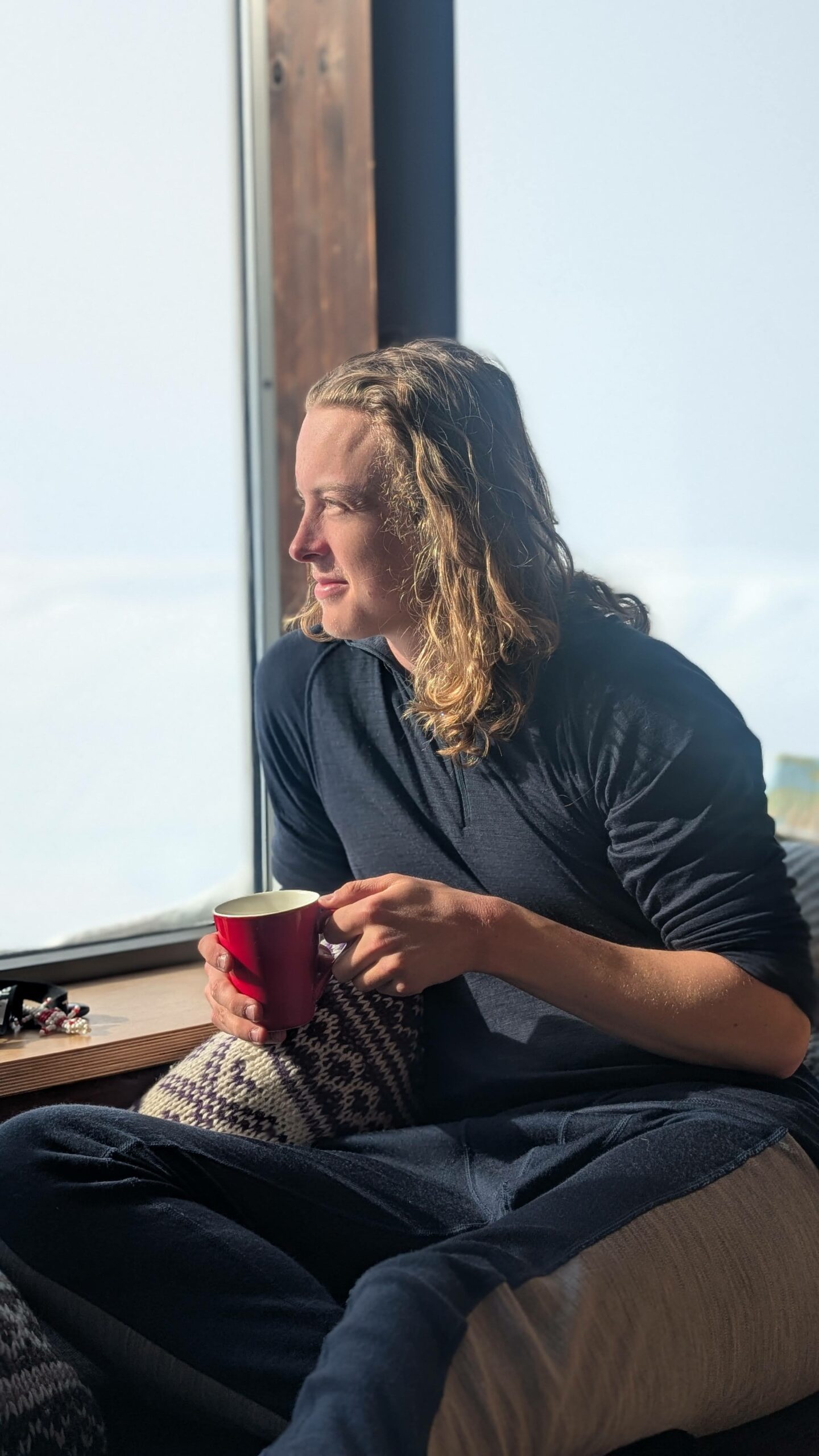 En gutt kikker ut vinduet med en kaffekopp i hånda