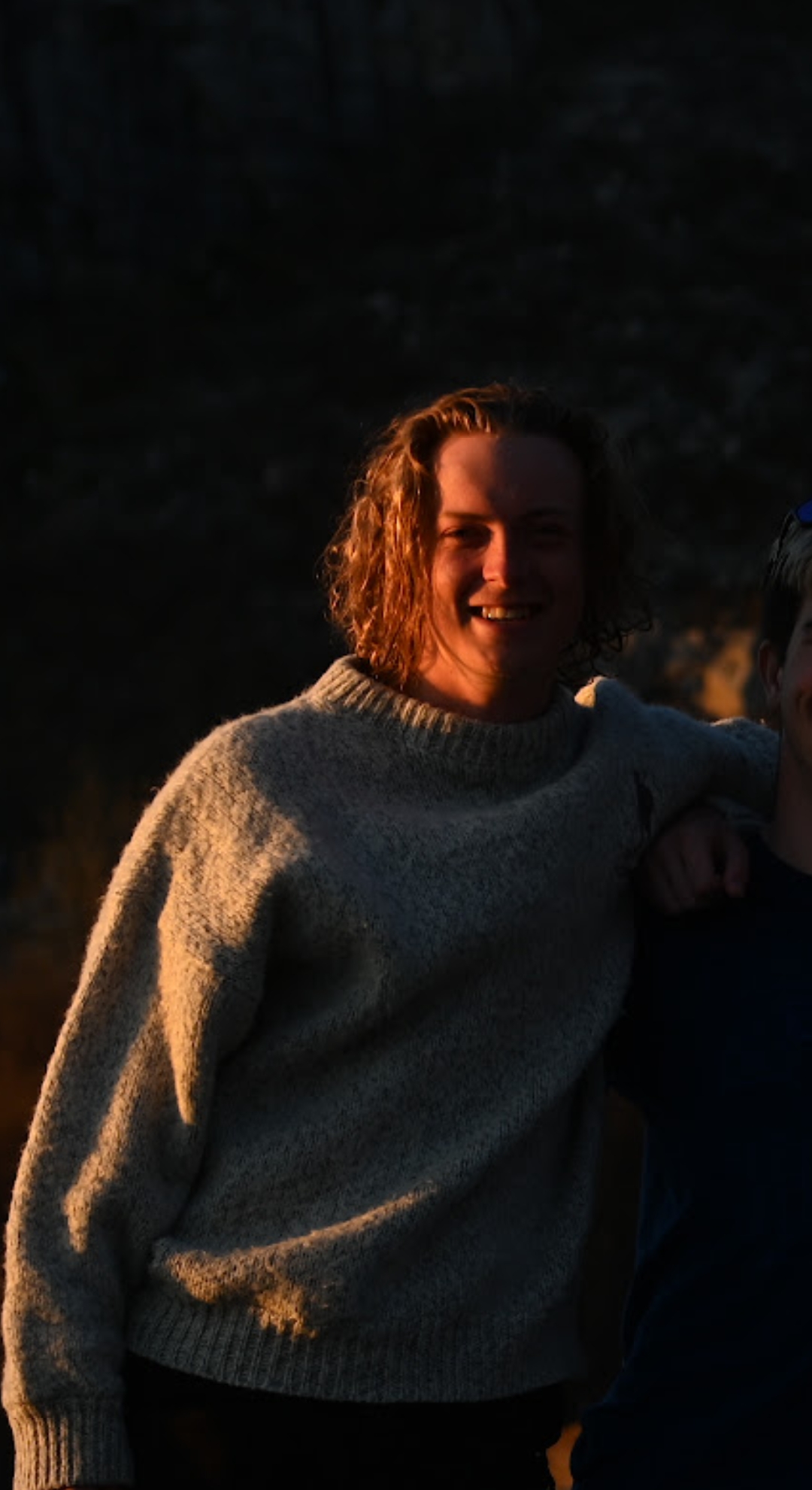 En gutt smiler i kamera. Det er mørkt