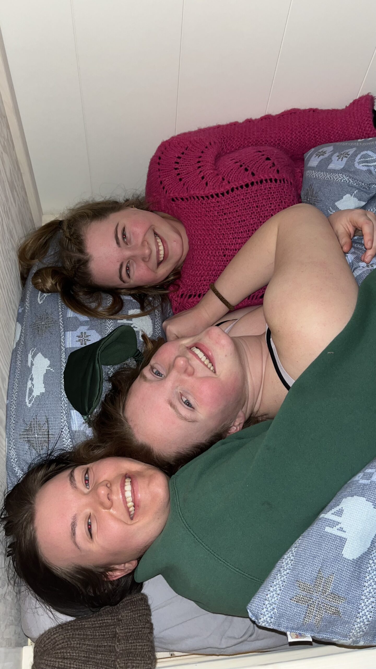 Tre gode venner ligger i senga og smiler